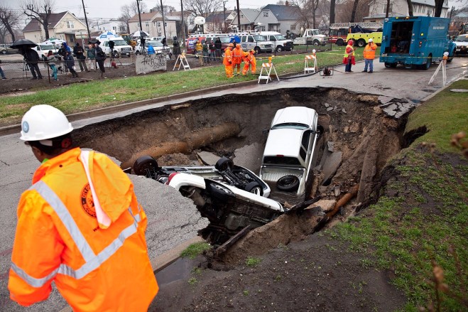 Large sink hole with auto under asphalt in multi-family residential area.